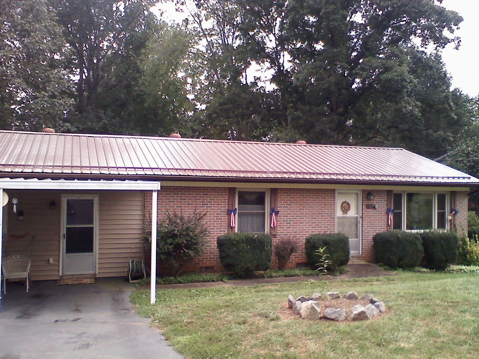 Bronze metal roof and carport on a brick ranch home — Roof Repair work by our crew in Jamestown